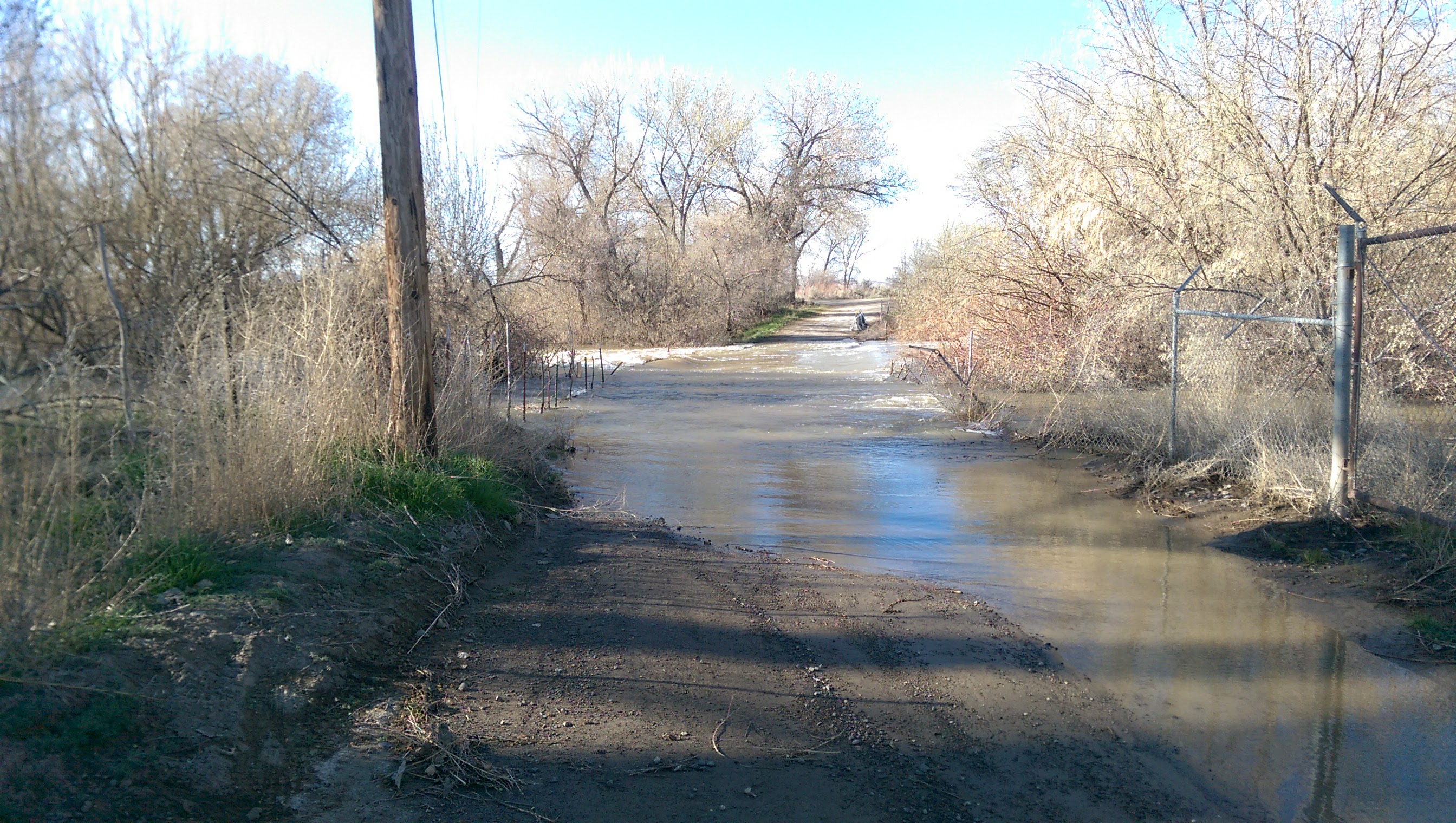 Picture of a dirt road where floodwaters have overtaken the road and made it impassible. 